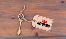 Key and a note on a wooden table with text - Tax Reforms